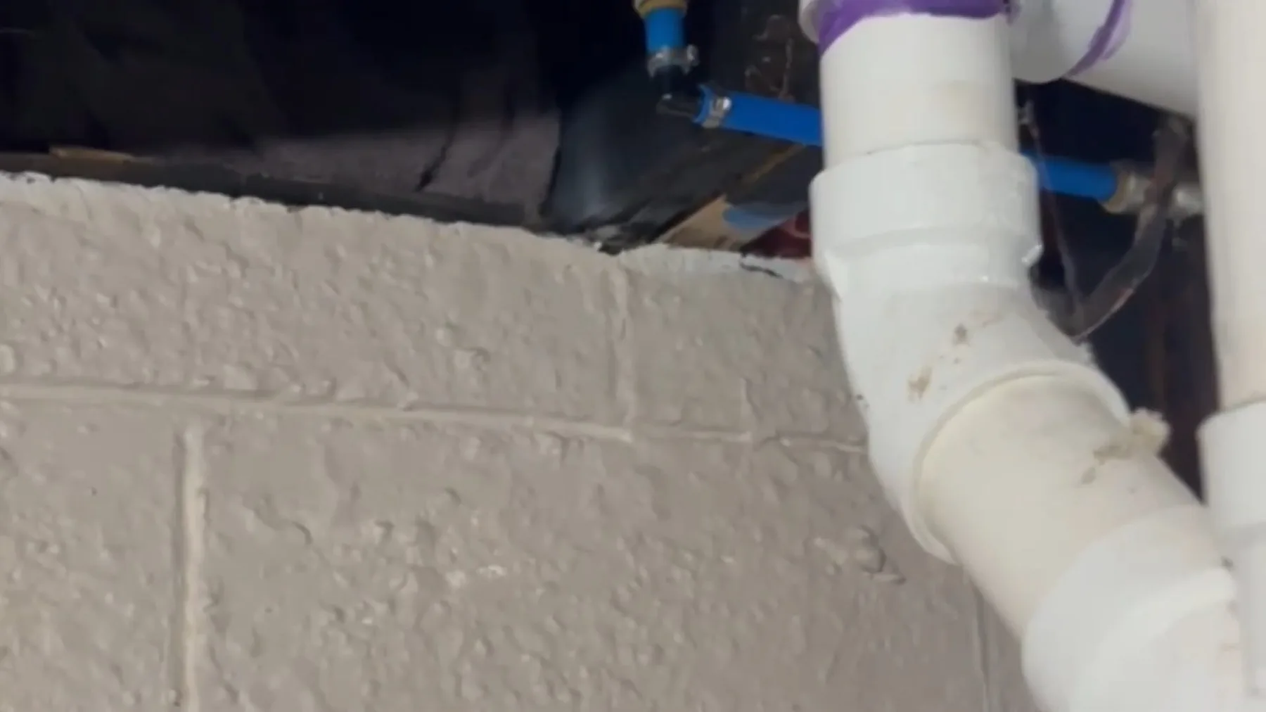 Close-up of white PVC drain elbow on brick wall